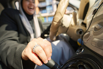 Smiling arab woman changing gear in car
