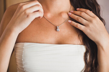 Bride puts on jewelry during wedding preparations