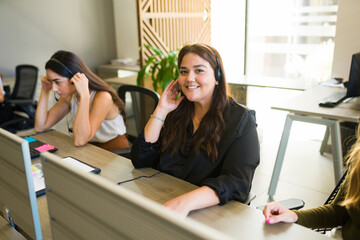 Hispanic customer support agent looking happy at the call center