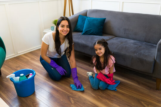 Happy young mother and daughter cleaning the floor together