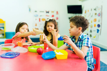 Kindergarten kids learning to share their lunch food