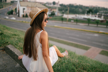 Portrait of a relaxed woman with hat looking forward at the horizon cityscape in the background copy space - 520354994