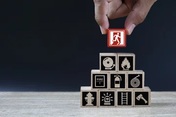 Foto op Plexiglas Hand choose cube wooden toy block stack with door exit sing or fire escape with fire prevent icon and fire extinguisher and emergency prevention or protection symbol for safety and rescue. © Eakrin