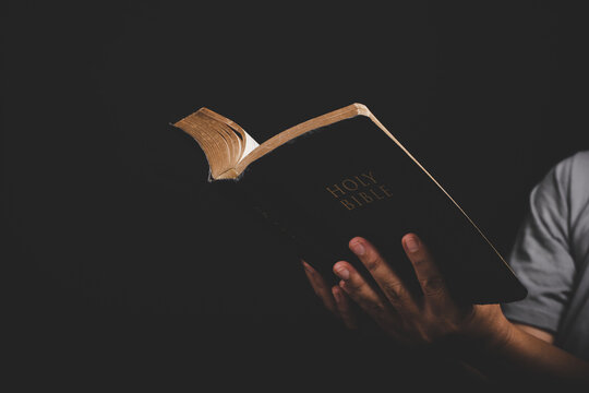 Close up of christian woman hand holding holy bible pray and worship for thank god in church with black background, adult female person are reading book,