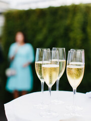 Five glasses of ice-cold champagne sit on a white table.