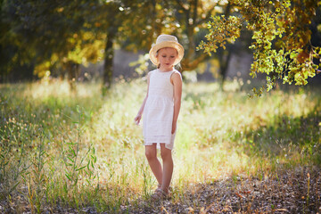 4 year old girl in white dress and straw hat walking in a garden in Provence, France