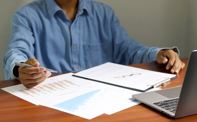 Businessman using laptop to analyze graphs and charts on his desk. Successful work planning