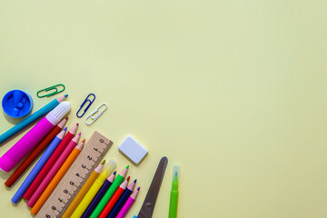 Banner with school supplies on yellow background. Colored pencils, felt-tip pens, eraser, paper clip, scissors, sharpener. Back to school.