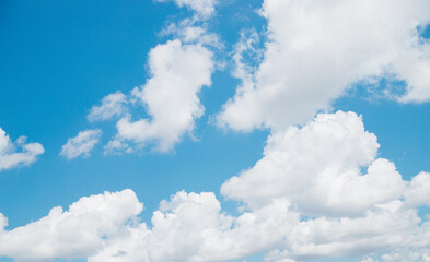 White clouds of air against a blue sky. A clear day and good weather. The sun is shining brightly. Spring or summer day.