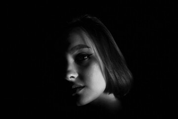 Beautiful female face in the shadows in black and white