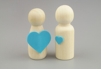 Different love feelings in couple concept. Female wooden figure with big heart sticker and male figure with small heart.