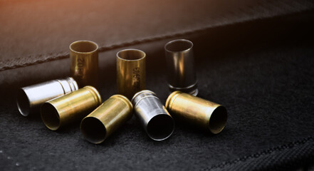 Group of 9mm bullet shells on black leather floor background, soft and selective focus.