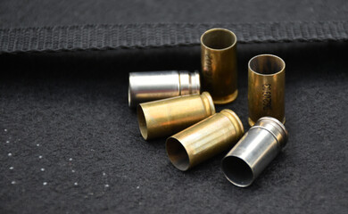 Group of 9mm bullet shells on black leather floor background, soft and selective focus.