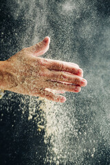 Fototapeta premium Hands with flour on a dark background