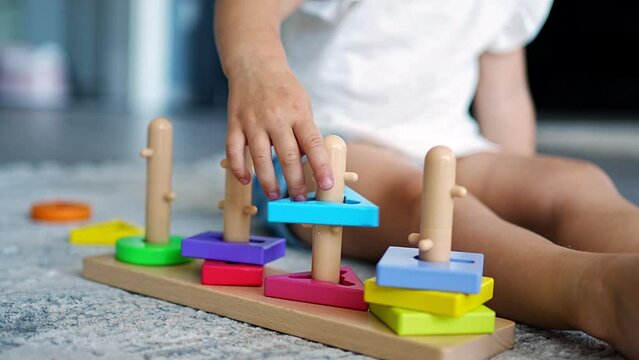 Cute caucasian little girl playing on the floor at home with eco wooden toys. Montessori toy. The child playing educational games.