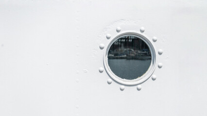Round porthole on the ship white wall.