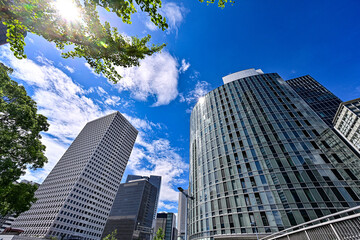 太陽がキラリと輝く青空背景に大阪梅田のビルを見上げた風景　【大阪風景】