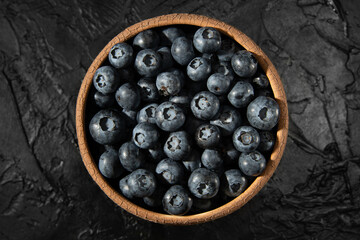 Blueberries in a plate on a black background. Recipes with berries. Healthy Ingredients.