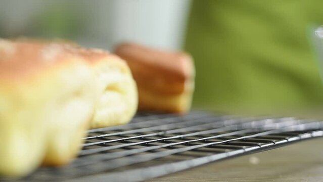 Female hand takes fresh Parker House roll.
