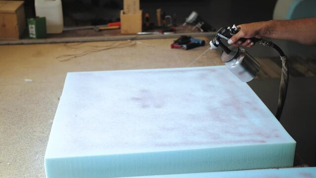 The factory for the manufacture of upholstered furniture. Gluing of foam rubber. The process of assembling and gluing upholstered furniture. Close-up. Unrecognizable 