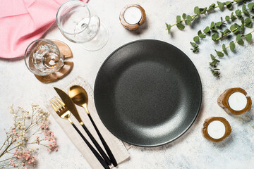 Table setting with plate, green leaves and cutlery at white kitchen table. Top view.