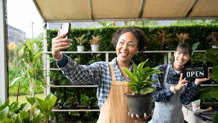 Portrait of mixed-races beautiful women partner owner standing in own tree shop and smiling to camera. Asian and African American females business partners working garden store. Business concept.