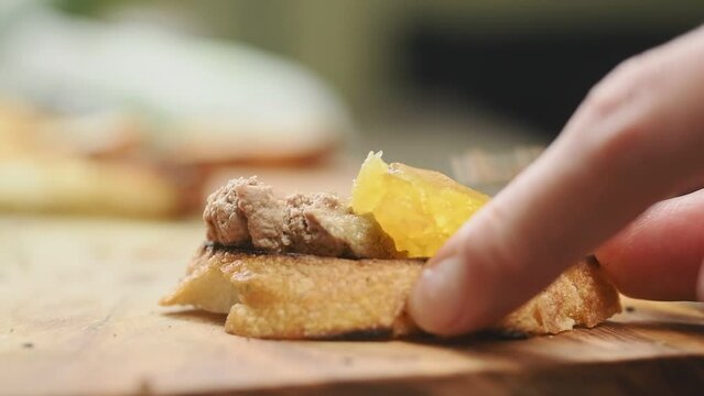 The cook spreading chicken liver pate with apricot and wine gelee on toasted bread.
