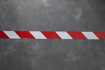 Barrier tape red and white at cement floor background. Signal warning tape on concrete wall