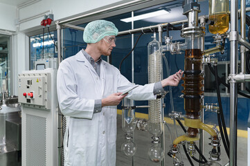 Inspector caucasian scientists are in the machine room extracting oil and cannabis seeds	