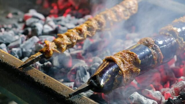 Close-up of eggplant kebab on skewers grilling on brazier. Turkish traditional kebabs grill on coal