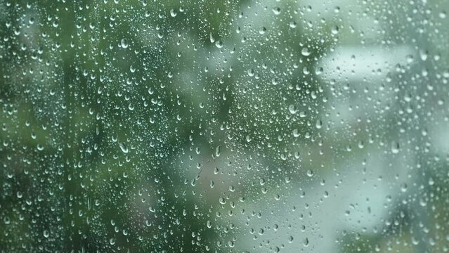 Close-up of Water Drops on Glass of Window. Drops Roll Down During Heavy Summer Rain. Thunderstorm with Strong Gusts of Wind. 4K.