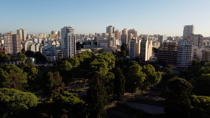 Drone shot of idyllic Centenario Park surrounded by giant skyscraper city of Buenos Aires during sunset