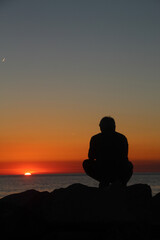 silhouette of a person sitting on a rock