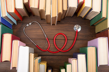 Medical degree education concept - stack of books in heart shape and stethoscope on the library...