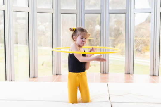 Little blonde girl with piggy tails playing with hula hoop