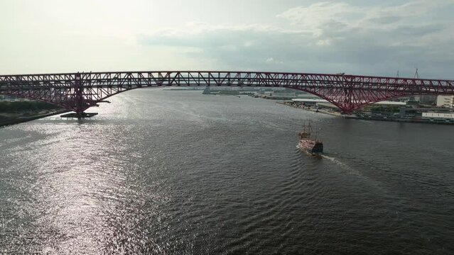 Flying behind old pirate ship sailing under modern bridge
