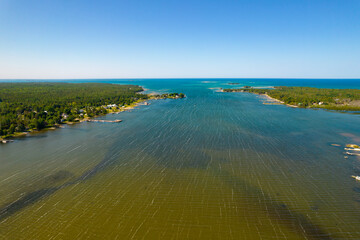 Lake at summer with wooden cottages and log cabins at the lakeshore in North America. Rural area view with green forest and lake in peninsula. Fishing Lodge at waterfront an summer huts with terrace.