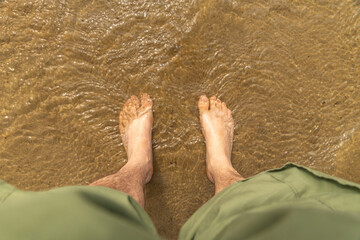 Tourist cooling his legs after hiking in Singing Sands shallow waters, Bruce Peninsula National...