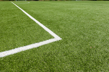 Fototapeta na wymiar Green synthetic artificial grass soccer sports field with white corner stripe line