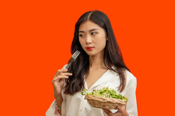 Vegetarian concept, Healthy woman eating sunflower sprouts standing isolated over orange background