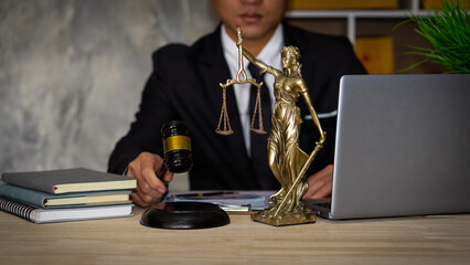 Business lawyers work hard at their desks with books and papers. The judge uses a hammer at the...