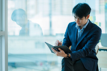 Handsome young Asian businessman sitting alone in the office