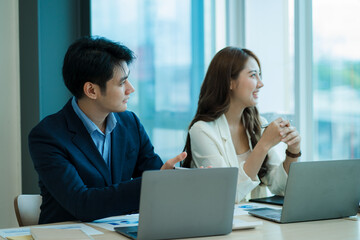 Obraz premium Two young Asian businessmen working together at the Financial Graph computer office. Share ideas, discuss and train business plans.