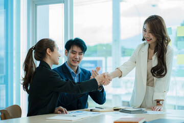 Two successful Asian business partners in elegant outfits join hands for a casual business group teamwork deal. Clap your hands in the modern office. ​​Approved by partners