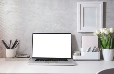 Fototapeta premium Bright modern home office with laptop, supplies and flower pot on white table. Empty screen for your advertise text.