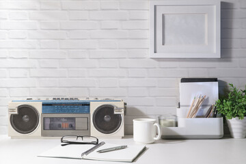 Vintage radio, coffee cup, notebook and potted plant on white table with daylight from the window. Copy space for advertise text.