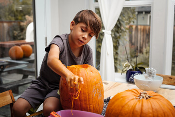 child carving a pumpkin