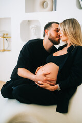 Future mother and father clasped pregnant big tummy. husband hugs pregnant wife. Happy family resting at home