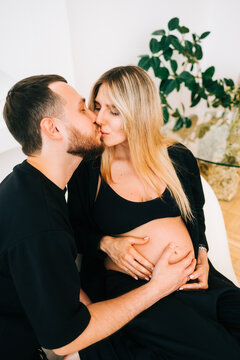 Future mother and father clasped pregnant big tummy. husband kiss pregnant wife. Happy family resting at home