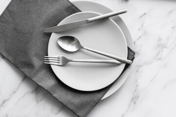 Dining table setting. Grey plate with silver cutlery on the linen napkin. Minimalism style.